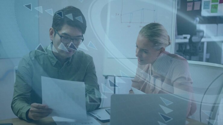 Man flipping report, woman leaning over laptop, triangular overlay sweeping for business review