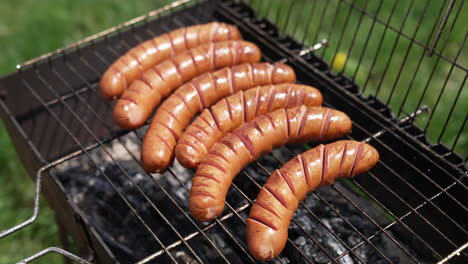 grilled sausages roasting on barbecue grill outdoors. grilled food frying and smoking in charcoal grills. tasty delicious sausages. street food for picnic and camping.