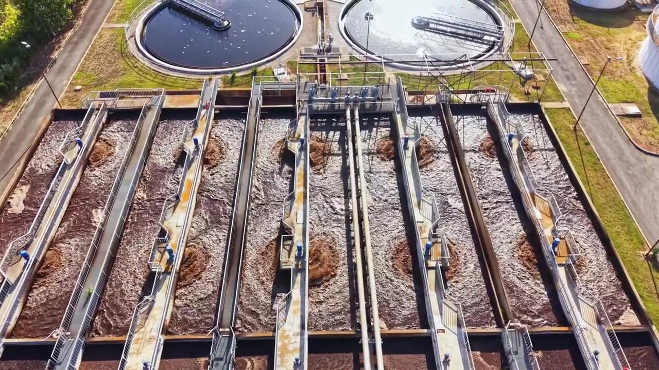 Water treatment plant in operation with multiple tanks and equipment visible at a wastewater facility during daytime
