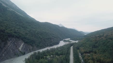 aerial view, drone flight along the glenn highway and the matanuska river in the chugach mountain range of central alaska on a cloudy summer day