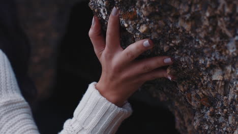 close up woman hand touching rock exploring seaside enjoying adventure