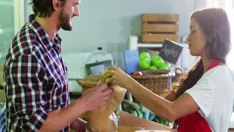 female staff assisting man in selecting fresh fruits