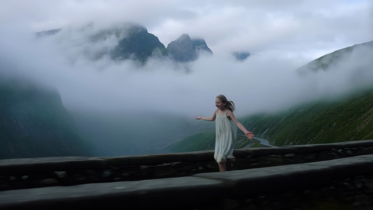 A girl playfully running on a mountain road amidst misty clouds