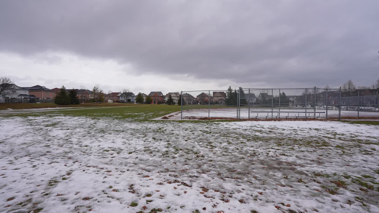 Campo coperto da chiazze di ghiaccio e neve al Kinross Park, Oshawa, Ontario, Canada.