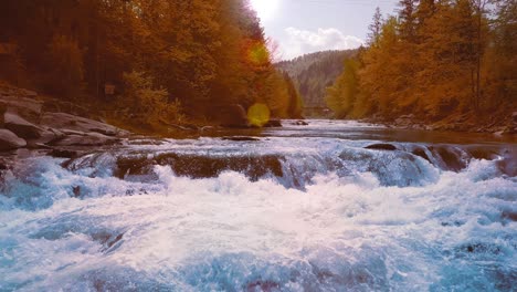 a low rapid flight over the rushing mountain river, blue in the middle of the forest and mountains. sunset time. the sun's rays give orange flare. the concept of treatment of urological diseases and prostatitis, freedom of decision-making, fresh natural