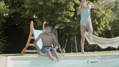 children diving into swimming pool in slow motion.