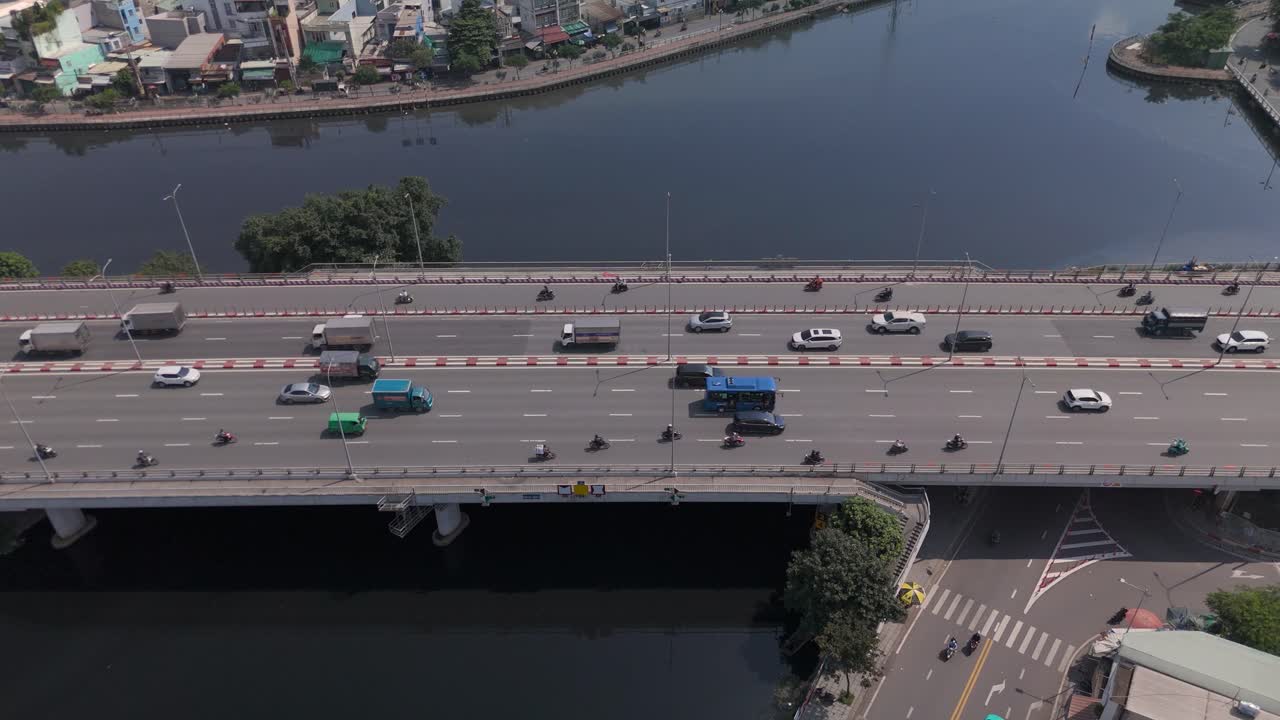Aerial view of busy freeway over river with urban sprawl on sunny clear day high static angle