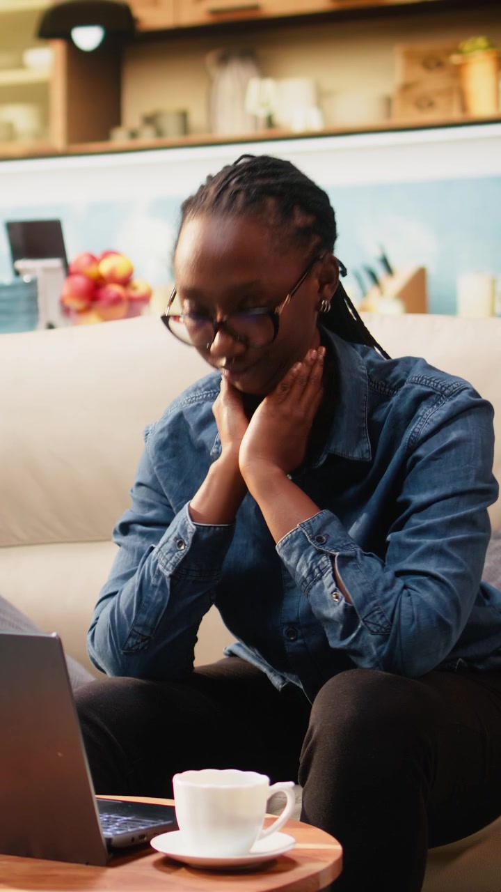 Vertical Video Woman freelancer stretching on couch and relaxing her upper back muscles