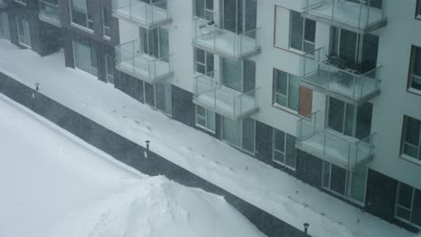 heavy snow falls on residential apartment building with windows and balconies