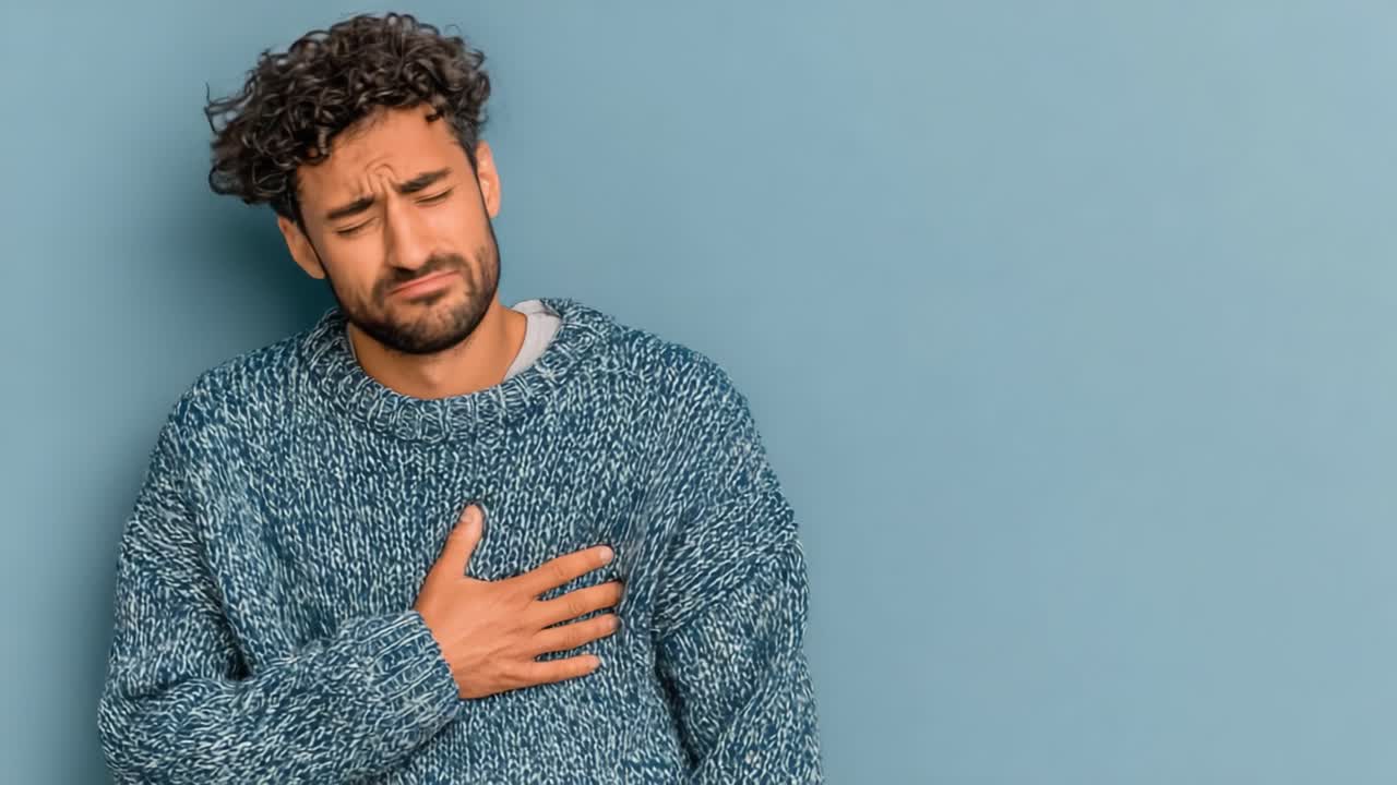 Un individuo preoccupato che esprime disagio mentre si porta una mano al petto su uno sfondo blu calmo, evidenziando vulnerabilità ed empatia nelle emozioni umane.