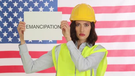 woman in hard hat holding 'emancipation' sign against american flag