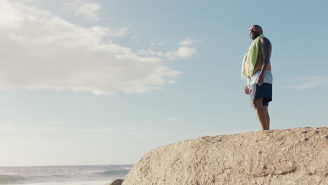 happy-african-american-man-on-beach-smiling-arms-raised-enjoying-beautiful-seaside-morning-feeling-positive-on--summer-vacation