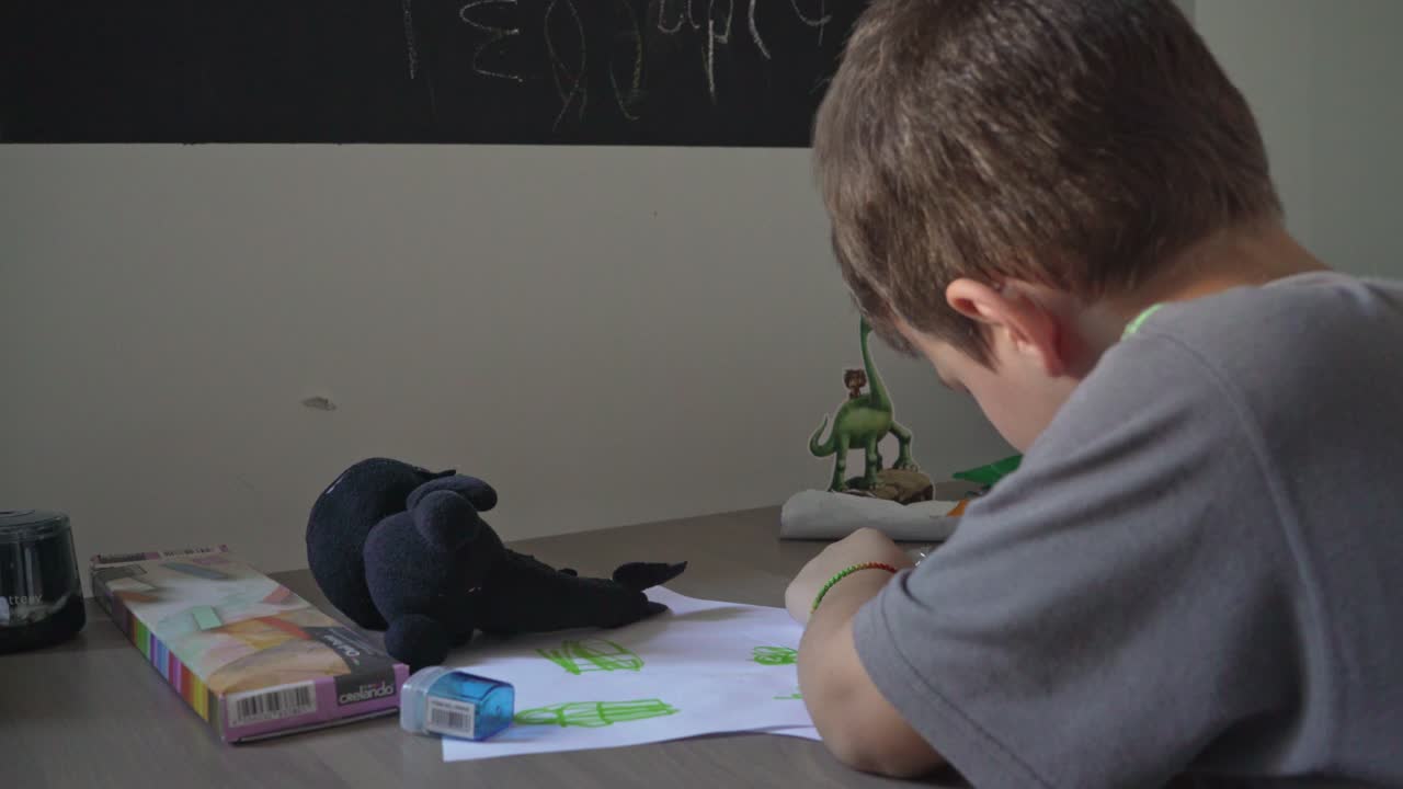 niño pequeño caucásico dibujando en el escritorio de su casa