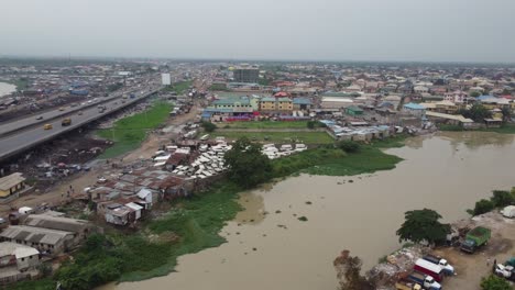 Cars-moving-speedily-on-brown-river-bridge-of-a-sub-urban-highway-with-a-Nigerian-flag-in-front-of-an-industry