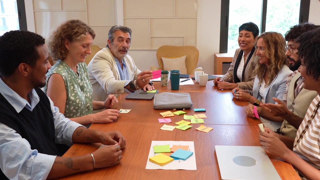 Divers zakelijk team werkt samen met post-its tijdens een kantoorvergadering.