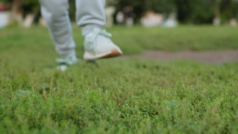 leg view of female athlete warming up with knee bend workout on grassy field near table tennis court during outdoor session under bright sky surrounded by green trees showcasing energy, and focus