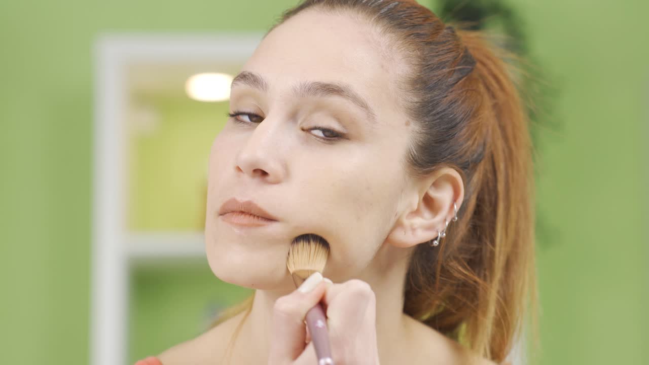Close-up of young woman doing makeup.
