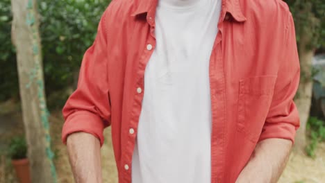 Portrait-of-smiling-senior-caucasian-man-holding-fresh-vegetables-in-garden