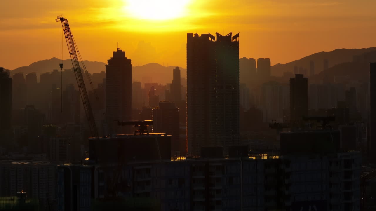 Tomada aérea ascendente com camadas compactadas de silhuetas de edifícios residenciais durante o pôr do sol dourado