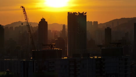 Toma-Aérea-Ascendente-Con-Capas-Comprimidas-De-Silueta-De-Edificios-Residenciales-Durante-La-Puesta-De-Sol-Dorada