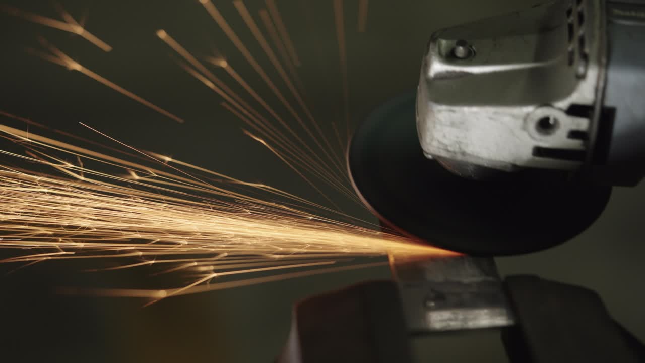 많은 불꽃을 일으키는 건설 각 밀러에서 작업자의 클로즈업