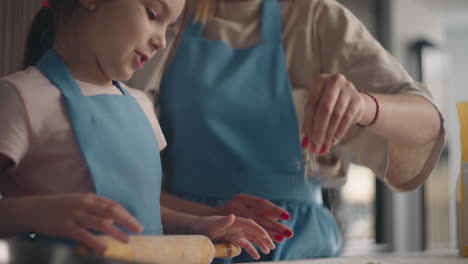 cute little girl is rolling out dough for pie child is helping to mother cooking in kitchen