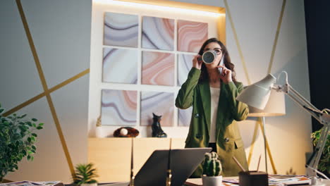 business woman chatting smartphone drinking tea at workplace. girl calling phone