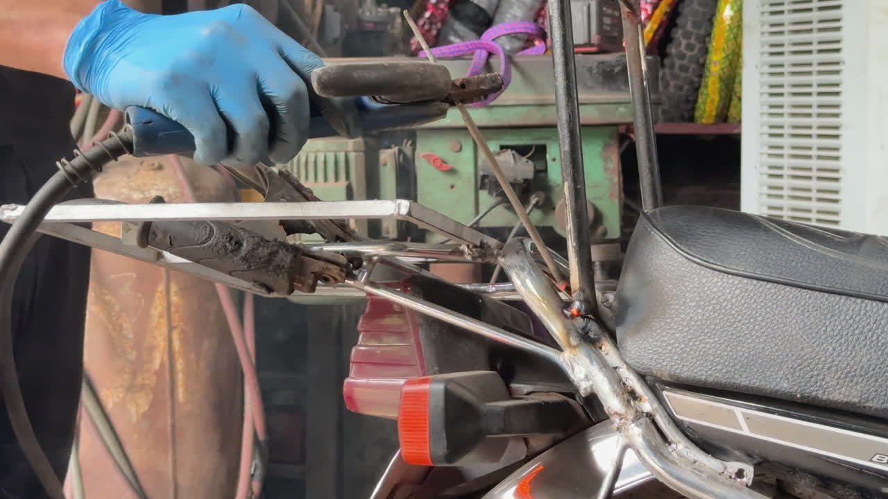 Close-up of electric welding on a motorbike handlebar in Hanoi, Vietnam. Sparks fly as a gloved mechanic repairs metal parts with precision in a garage setting.