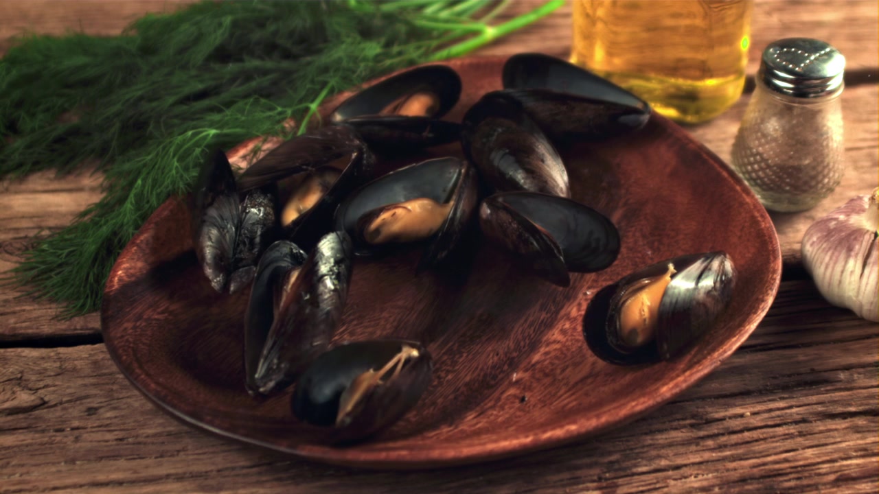 Mejillones frescos cayendo a cámara lenta sobre un plato de madera rústico