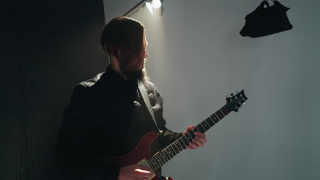 intense guitarist in black attire plays a red electric guitar, moving rhythmically against a pure white background, with dynamic camera zooms