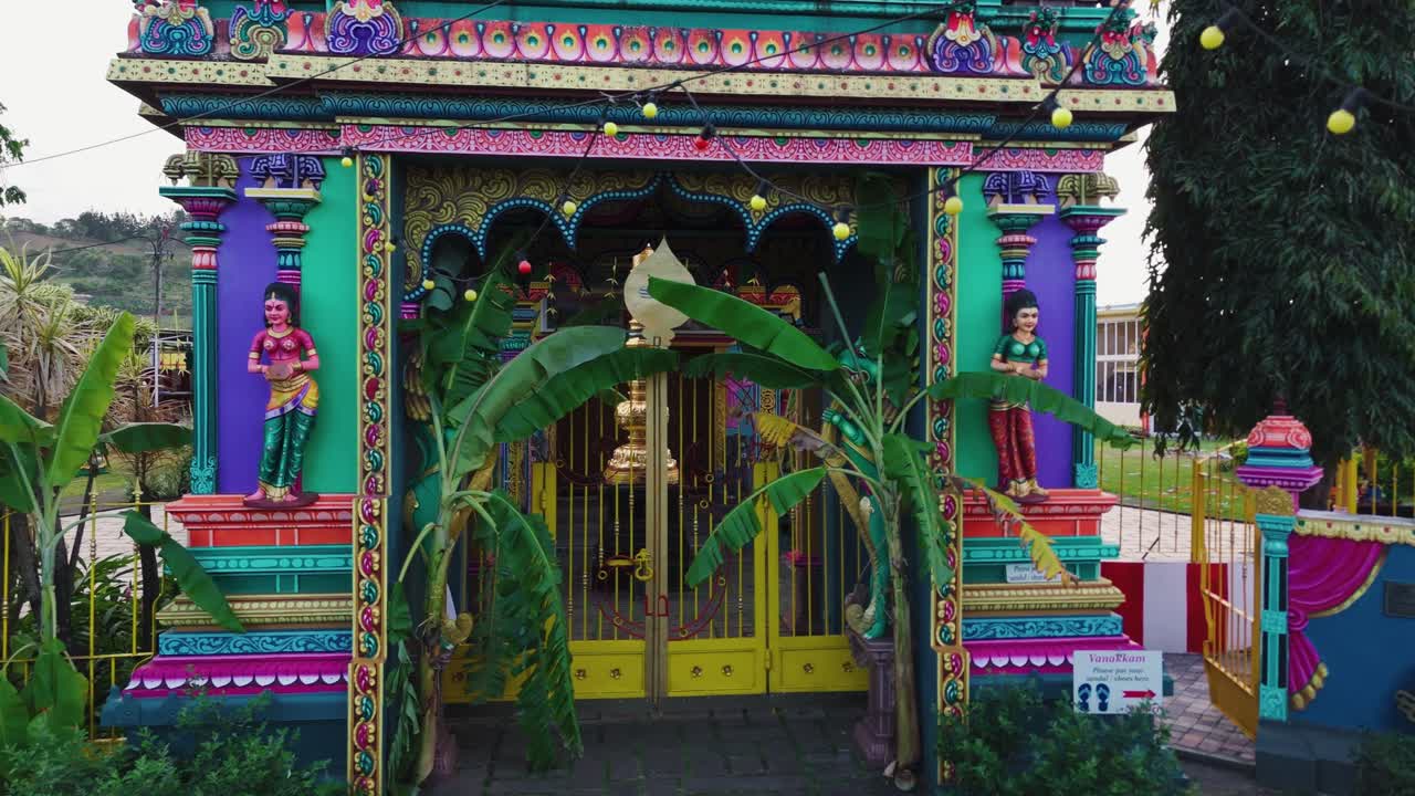 Low angle of Tamil Hindu temple gate richly decorated with vibrant patterns and sacred symbols, aerial approach