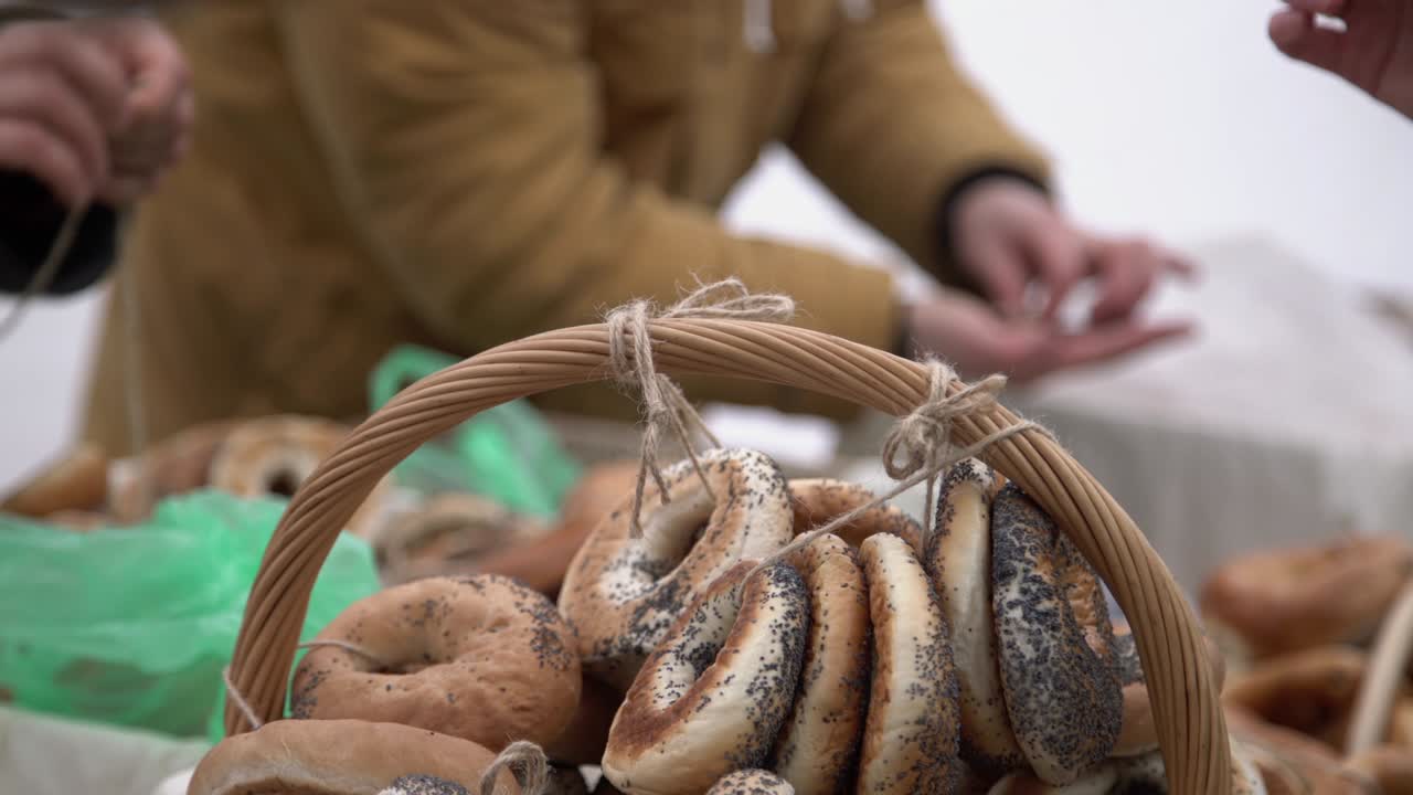 cliente comprando panes en forma de anillo sazonados con semillas de amapola en una tarifa de la ciudad. mano pagando dinero por bagels, anillo de pan