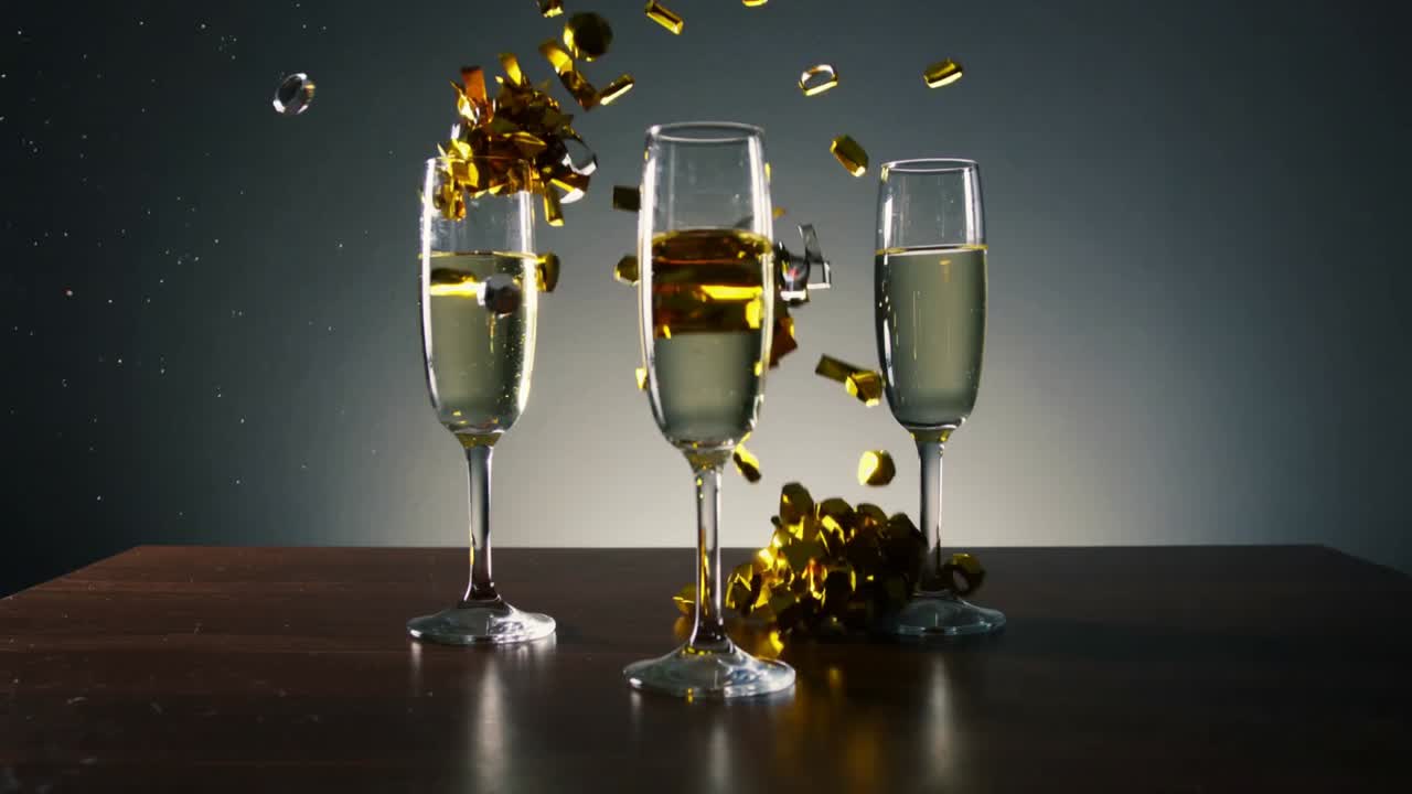 Una cascata di coriandoli dorati che colpisce tre flute di champagne su un tavolo di legno scuro, creando delle onde