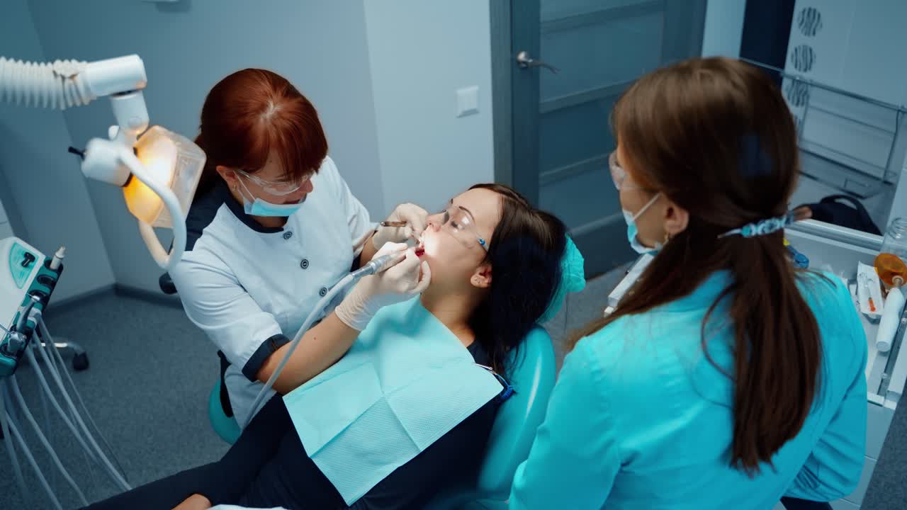 Female dentist and a client in dental chair. Professional stomatologist and assistant treating patient's tooth in a dental office. Top view.