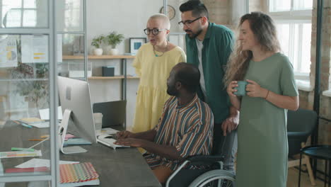 hombre afroamericano en silla de ruedas trabajando con un equipo de negocios en la oficina