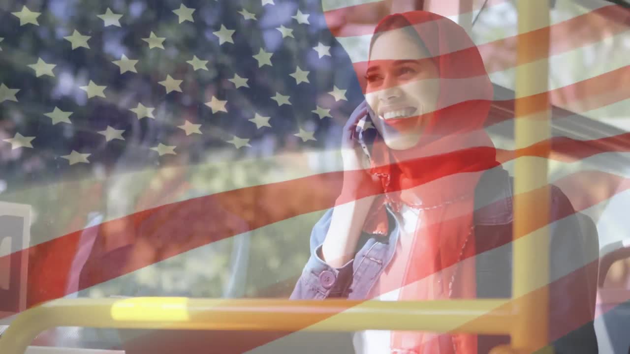 animación de la bandera estadounidense ondeando sobre una mujer de raza mixta en hijab usando un teléfono inteligente