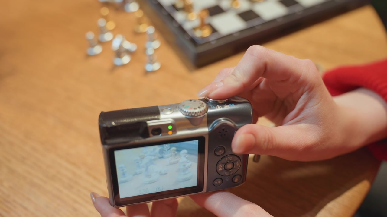 Primo piano di mani che fotografano pezzi degli scacchi con una fotocamera digitale