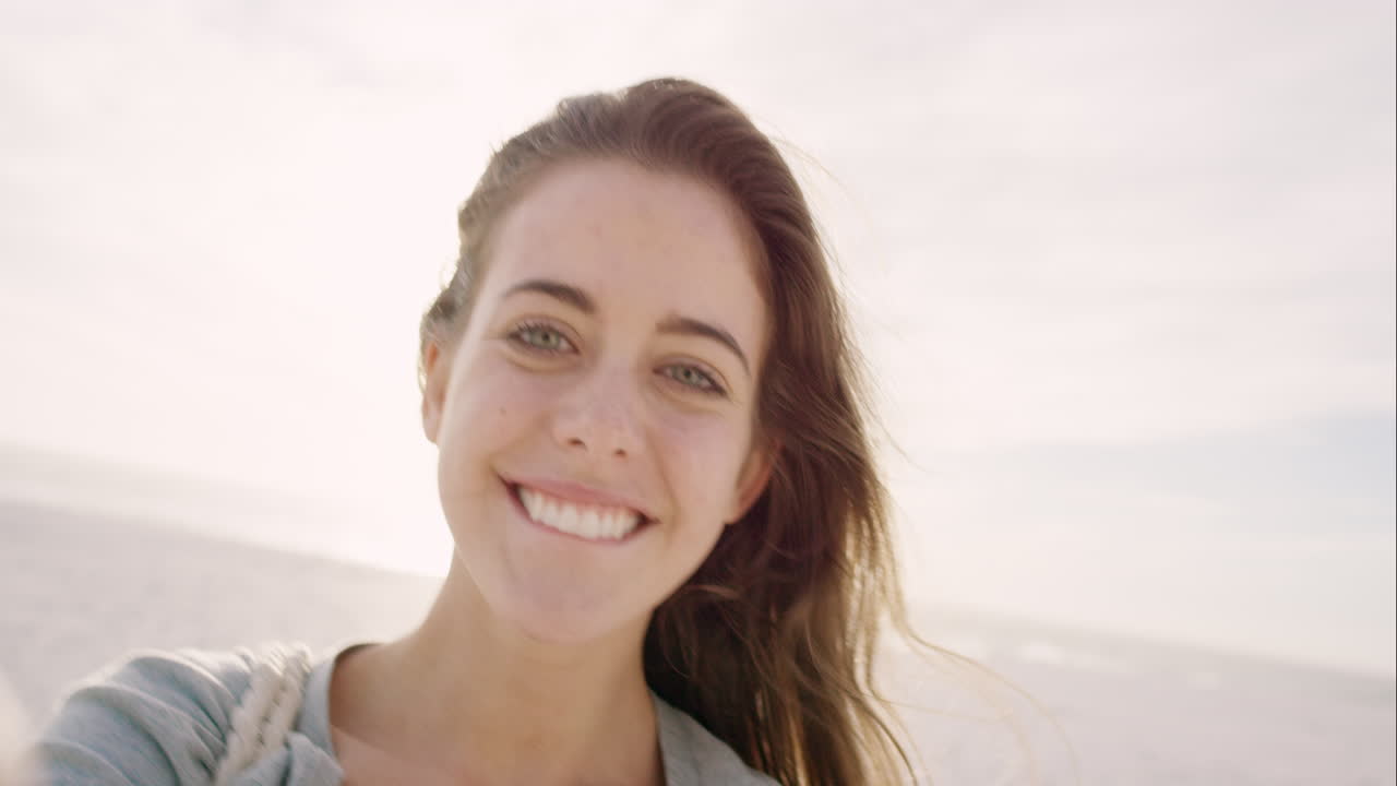 hermosa mujer tomando una selfie usando el teléfono en la playa al atardecer sonriendo y girando disfrutando de la naturaleza y el estilo de vida en vacaciones