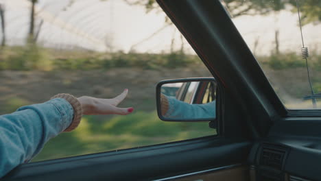 mujer con la mano en la ventana del coche sintiendo el viento soplando a través de los dedos conduciendo en el campo viajando en vacaciones de verano viaje por carretera disfrutando de la libertad en la carretera