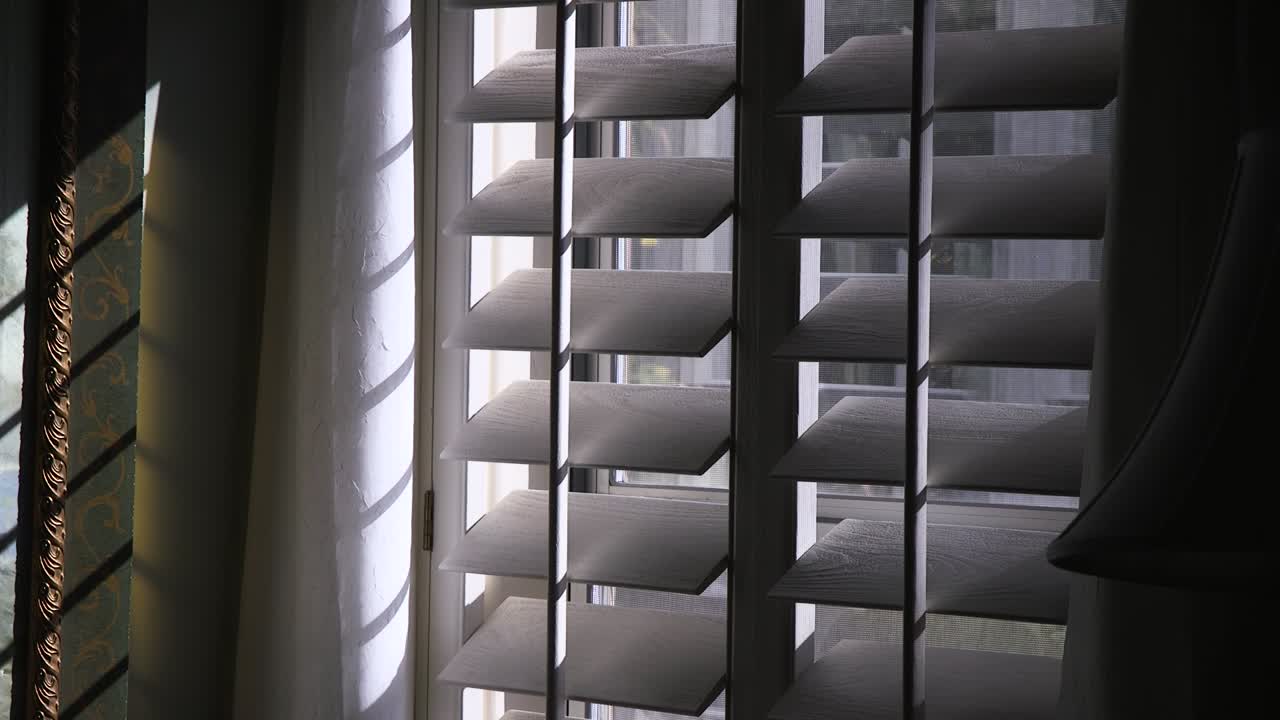 Light filters through white wooden shutters casting interesting shadows