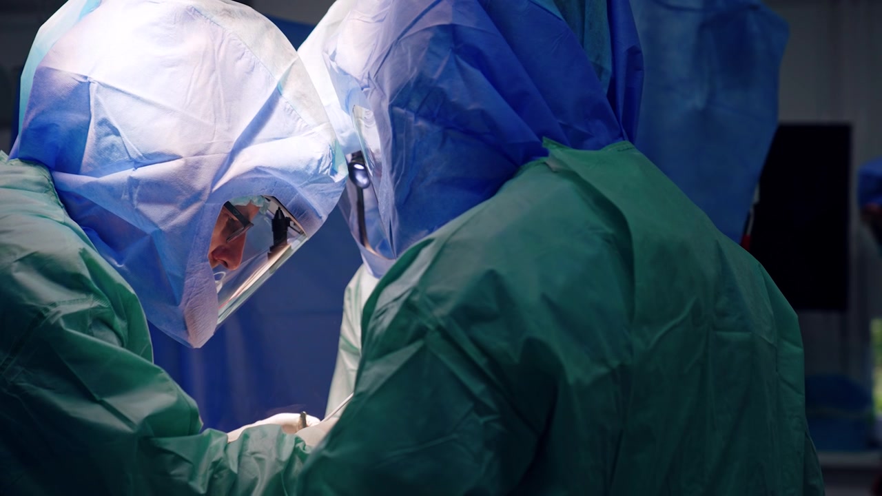 Professionisti della chirurgia concentrati, con caschi protettivi, usano con attenzione moderni strumenti chirurgici. Intervento chirurgico per la cura di un trauma in corso.