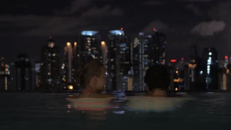 in pool on roof of a hotel in kuala lumpur malaysia couple in love looking to night city