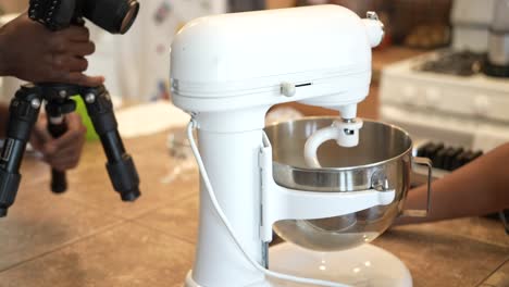 adjusting a camera and tripod to film a food preparation video at home