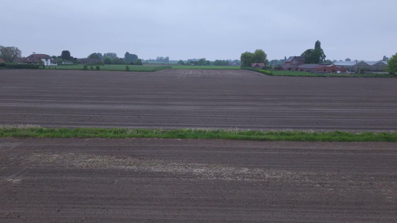 Ein Drohnenflug nach vorne enthüllt kultiviertes Ackerland, offene Felder und die umliegende Landschaft. Luftaufnahmen zeigen eine friedliche ländliche Szenerie unter einem bedeckten Himmel