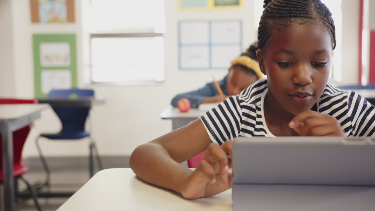 Using tablet, girl in school classroom focusing on learning activity