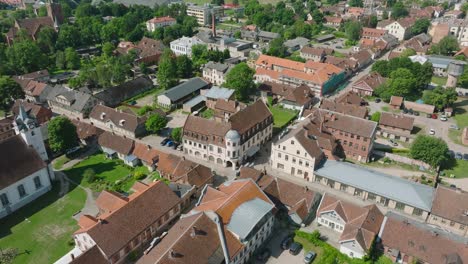 Aerial-establishing-view-of-Kuldiga-Old-Town-,-houses-with-red-roof-tiles,-sunny-summer-day,-travel-destination,-wide-drone-shot-moving-forward,-tilt-down