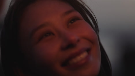 nahaufnahme von wunderkerzen, glückliche asiatische frau, die lächelnd silvester feiert und die feier zum unabhängigkeitstag am strand bei sonnenuntergang genießt