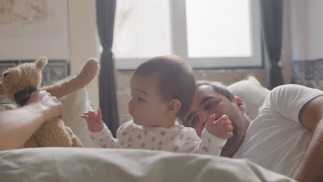 Glückliches-Paar,-Das-Am-Sonntagmorgen-Im-Bett-Liegt-Und-Mit-Seinem-Süßen-Baby-Spielt