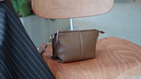 a small brown leather purse on a wooden chair in a cafe