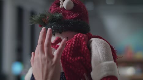 interior christmas design, white christmas tree with white lights being decorated by hands.